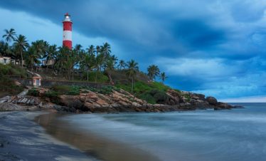Gathering storm on beach and lighthouse on sunset. Kerala, India